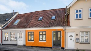 Un immeuble à deux étages, avec un toit recouvert de tuiles rouges, portant les numéros 36 et 32.