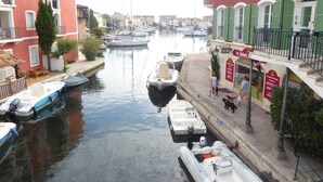 A narrow canal with boats docked on both sides, flanked by buildings with balconies and a café. - House - House btw. Cogolin and St. Tropez (Cogolin)