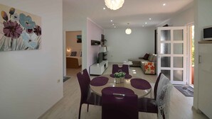 Un espace de salle à manger moderne avec une table ronde, des chaises violettes et un lustre.