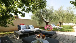 Un espace extérieur aménagé avec des fauteuils confortables, une table avec un magazine et un vase décoratif rempli de fleurs.