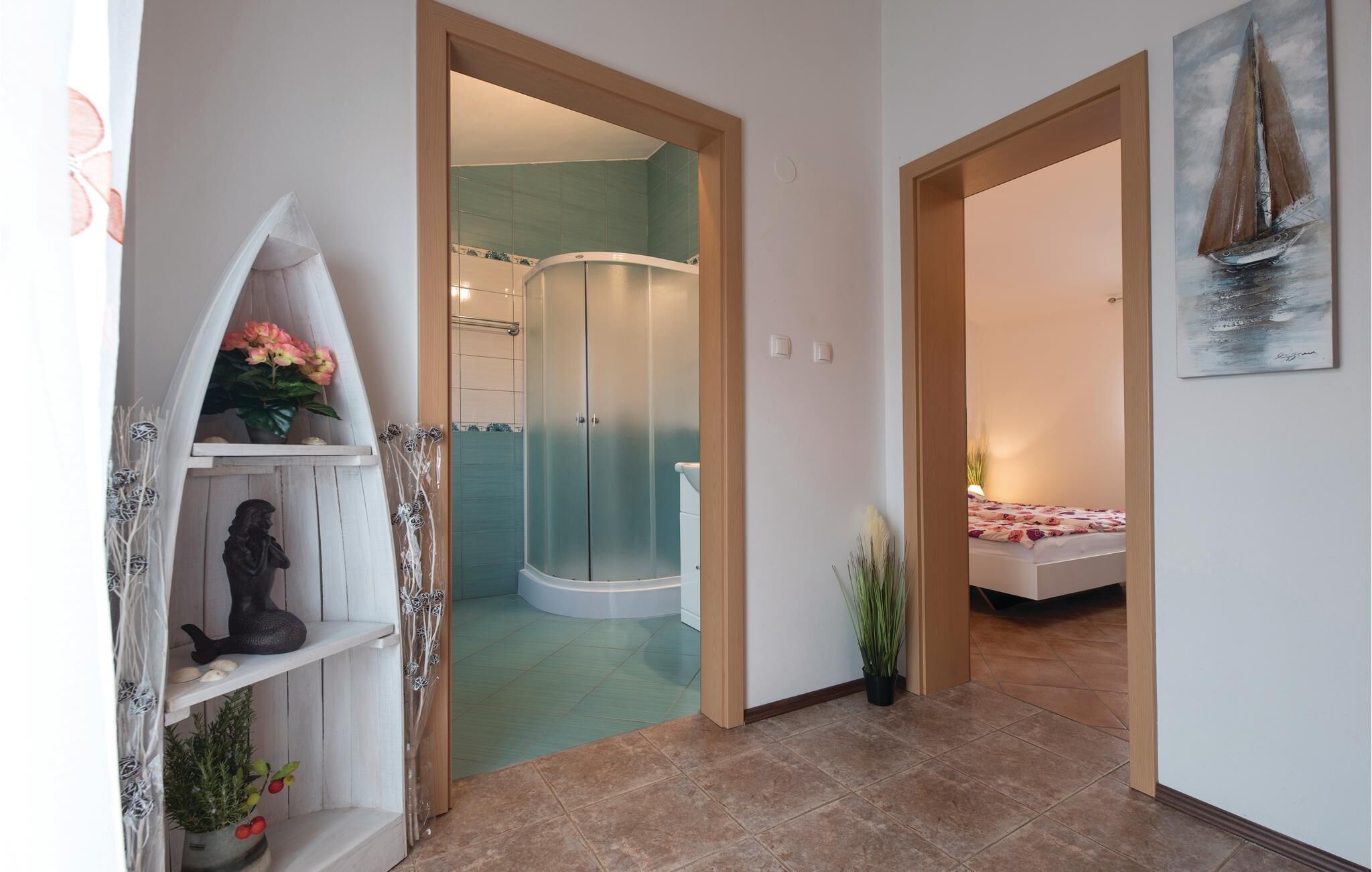 A hallway with a shower, a bed, and a painting on the wall.