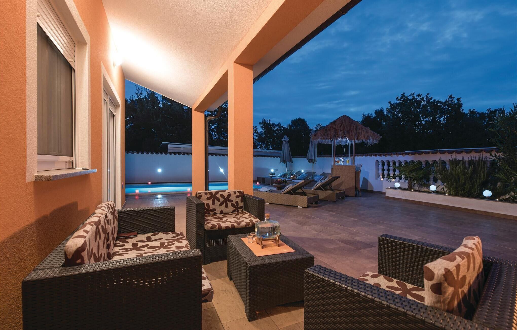 Une terrasse extérieure aménagée avec des meubles en osier, une piscine et un gazebo à toit de chaume.