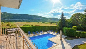 Une piscine avec des chaises longues, une table et une vue sur les montagnes et un lac.