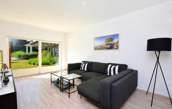 A modern living room with a sofa, a glass coffee table, a floor lamp, and a painting on the wall.