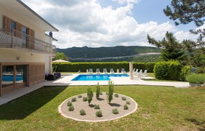 Relax by the pool surrounded by a lush lawn and garden, with lounge chairs for ultimate relaxation.