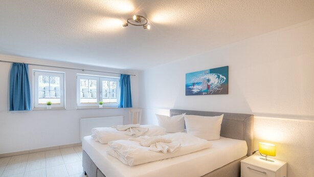 A clean, modern bedroom with a bed, bedside table, and a painting on the wall. - Apartment (Appartment) Curr 02 Garden Street -. Apartment (Appartment) Curr 02 Garden Street. (Heringsdorf)
