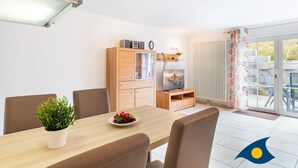 A modern dining area with a wooden table, chairs, a potted plant, and a television on a wooden cabinet. - Apartment (Appartment) Curr 02 Garden Street -. Apartment (Appartment) Curr 02 Garden Street. (Heringsdorf)