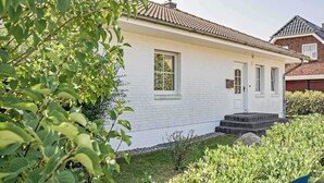 A single-story house with a white exterior, a tiled roof, and a small front porch. - Apartment (Appartment) Curr 02 Garden Street -. Apartment (Appartment) Curr 02 Garden Street. (Heringsdorf)
