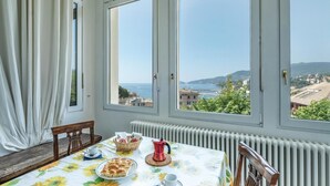 A dining area with a table set for two, a view of the sea, and a cityscape in the background. - Cozy apartment in Rapallo GE with WiFi (Rapallo GE)