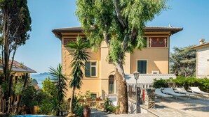 A Mediterranean-style building with a pool, surrounded by lush greenery and a clear view of the sea. - Cozy apartment in Rapallo GE with WiFi (Rapallo GE)