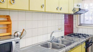 A kitchen with yellow cabinets, a stainless steel sink, a gas stove, and a microwave. - Awesome apartment in Santa Susanna (Santa Susanna)