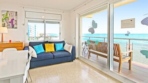 A modern room with a blue sofa, a wooden bench, and a large window offering a view of the sea. - Awesome apartment in Santa Susanna (Santa Susanna)