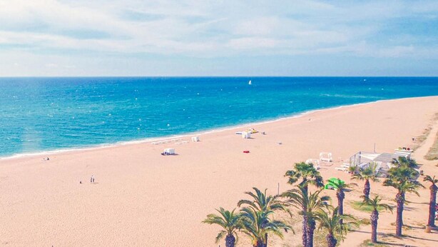 A beach with a clear sky, calm sea, and palm trees. - Awesome apartment in Santa Susanna (Santa Susanna)