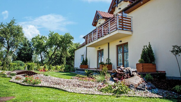 A two-story house with a balcony, surrounded by a well-maintained garden with various plants and a pebble pathway. - Amazing apartment in Goscino with WiFi (Goscino)
