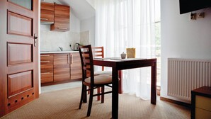A kitchen with wooden cabinets, a dining table with chairs, a radiator, and a TV mounted on the wall. - Amazing apartment in Goscino with WiFi (Goscino)