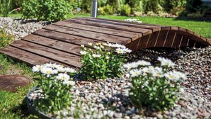 A wooden bridge over pebbles with white flowers in the foreground. - Amazing apartment in Goscino with WiFi (Goscino)