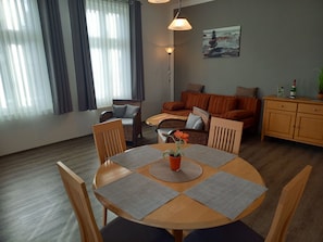 A cozy living room with a round wooden table, two sofas, and a dining area.