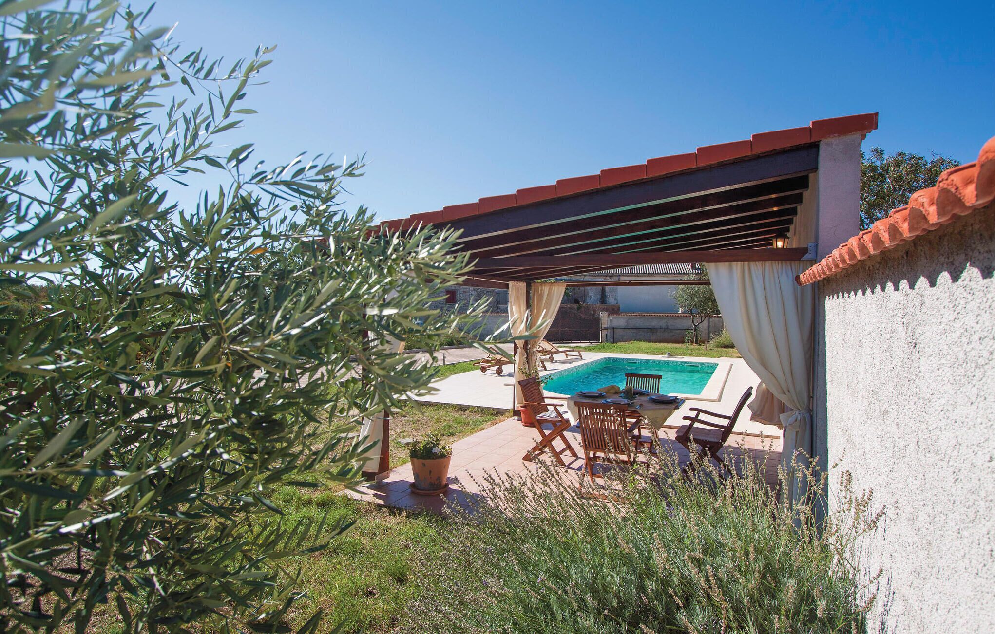 Zona exterior coberta amb piscina, seients i una pèrgola.