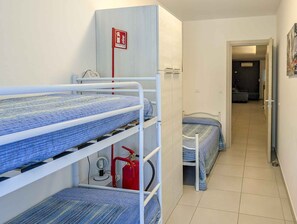 Ein Schlafsaalzimmer mit Etagenbetten, einem Feuerlöscher und einer Tür zu einem weiteren Raum.