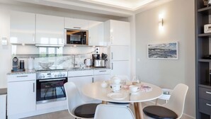 A modern kitchen with white cabinets, a built-in oven, and a dining area with a round table and chairs.