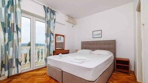 A bedroom with a large bed, a nightstand, a mirror, and a view of the outdoors. - Studio with air conditioning (Crikvenica)