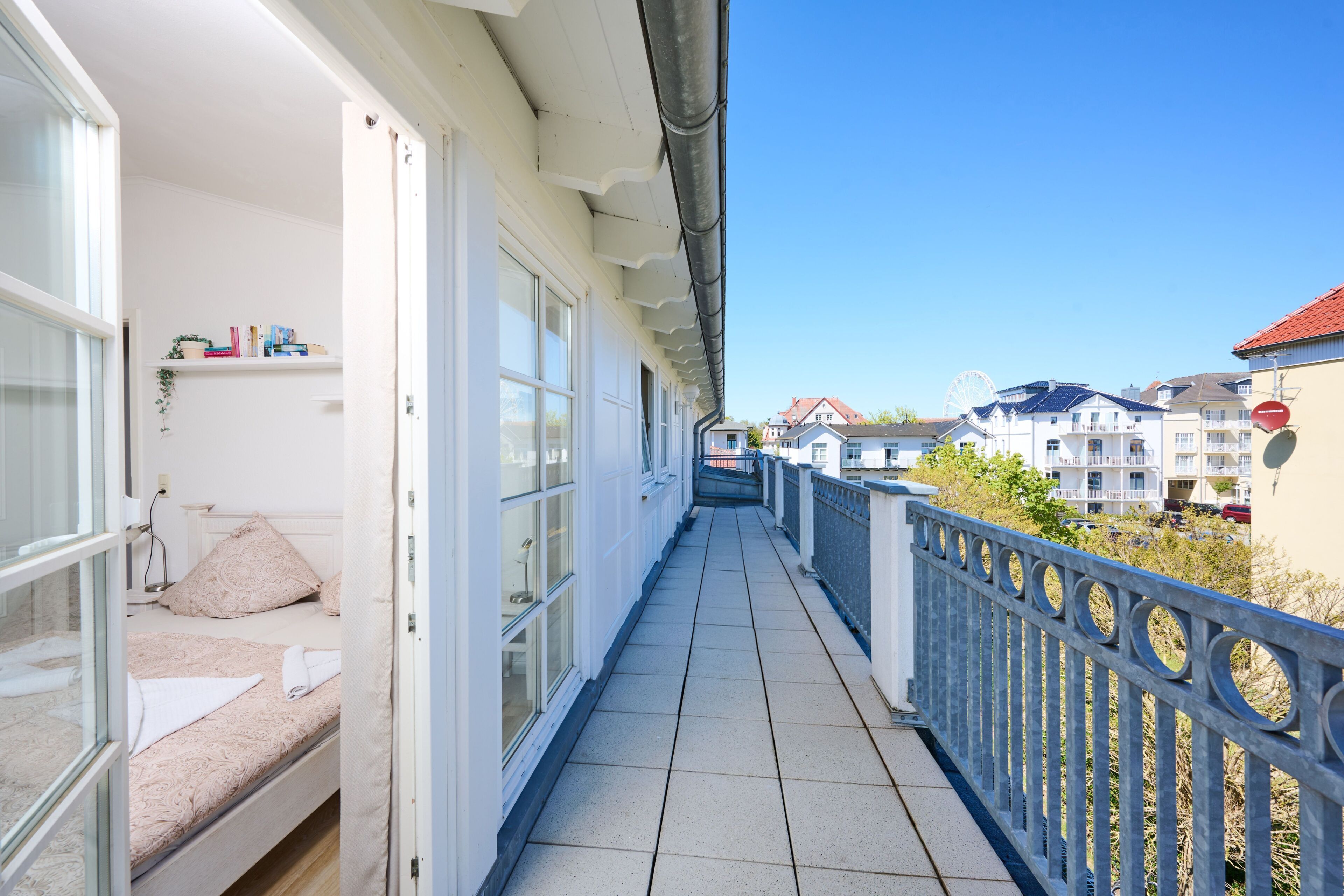 En balkon med en seng, et vindue og udsigt til andre bygninger.