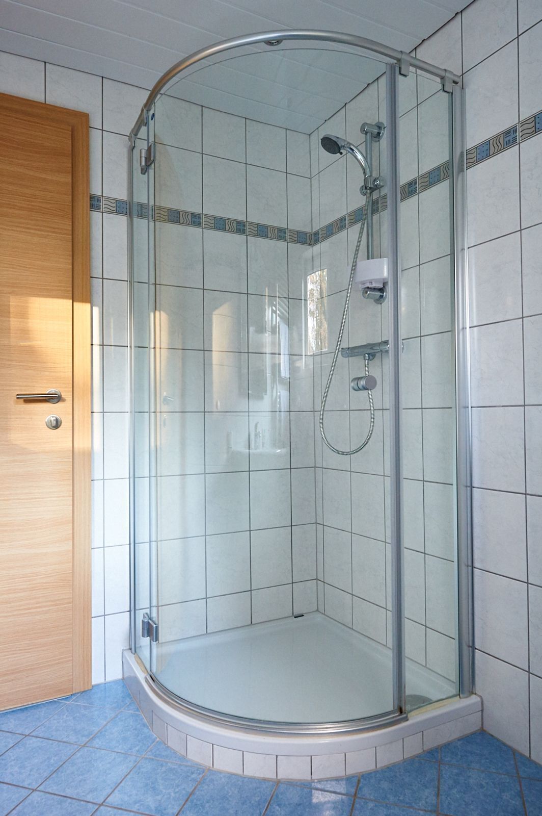 Eine Duschkabine mit Handbrause und Wandarmatur.