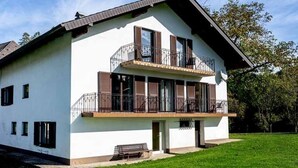 A two-story building with a balcony, a bench outside, and a grassy lawn.