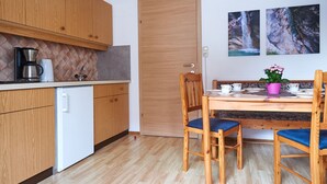 Une cuisine compacte dotée de meubles en bois, d’une machine à café, d’un évier et d’un coin repas comprenant deux chaises et une table.