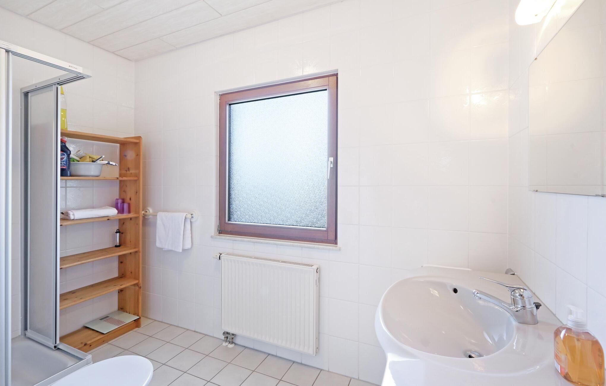 A bathroom with a toilet, sink, and shelves.