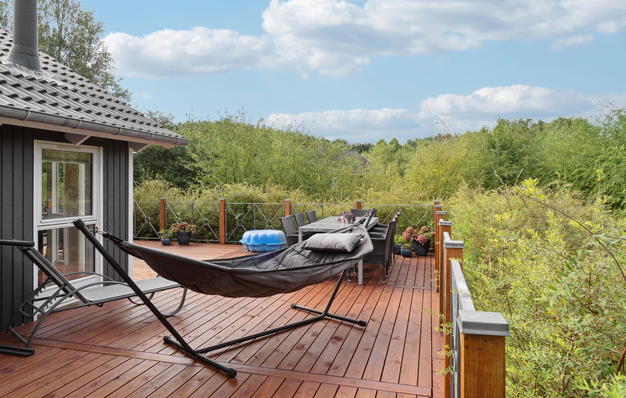 A wooden deck with a hammock, outdoor furniture, and potted plants.