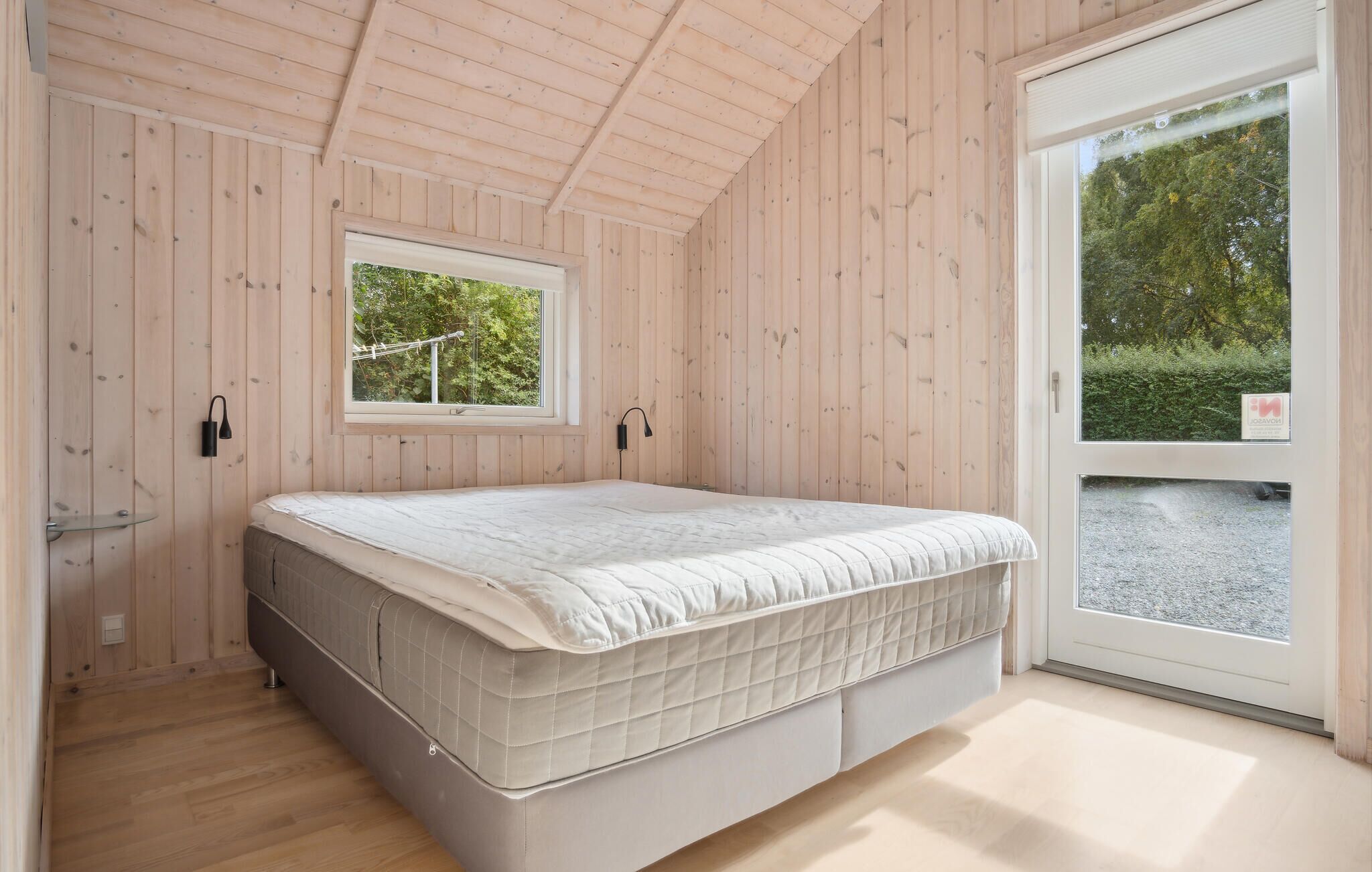 A bedroom with a bed, a window, and a door leading outside.
