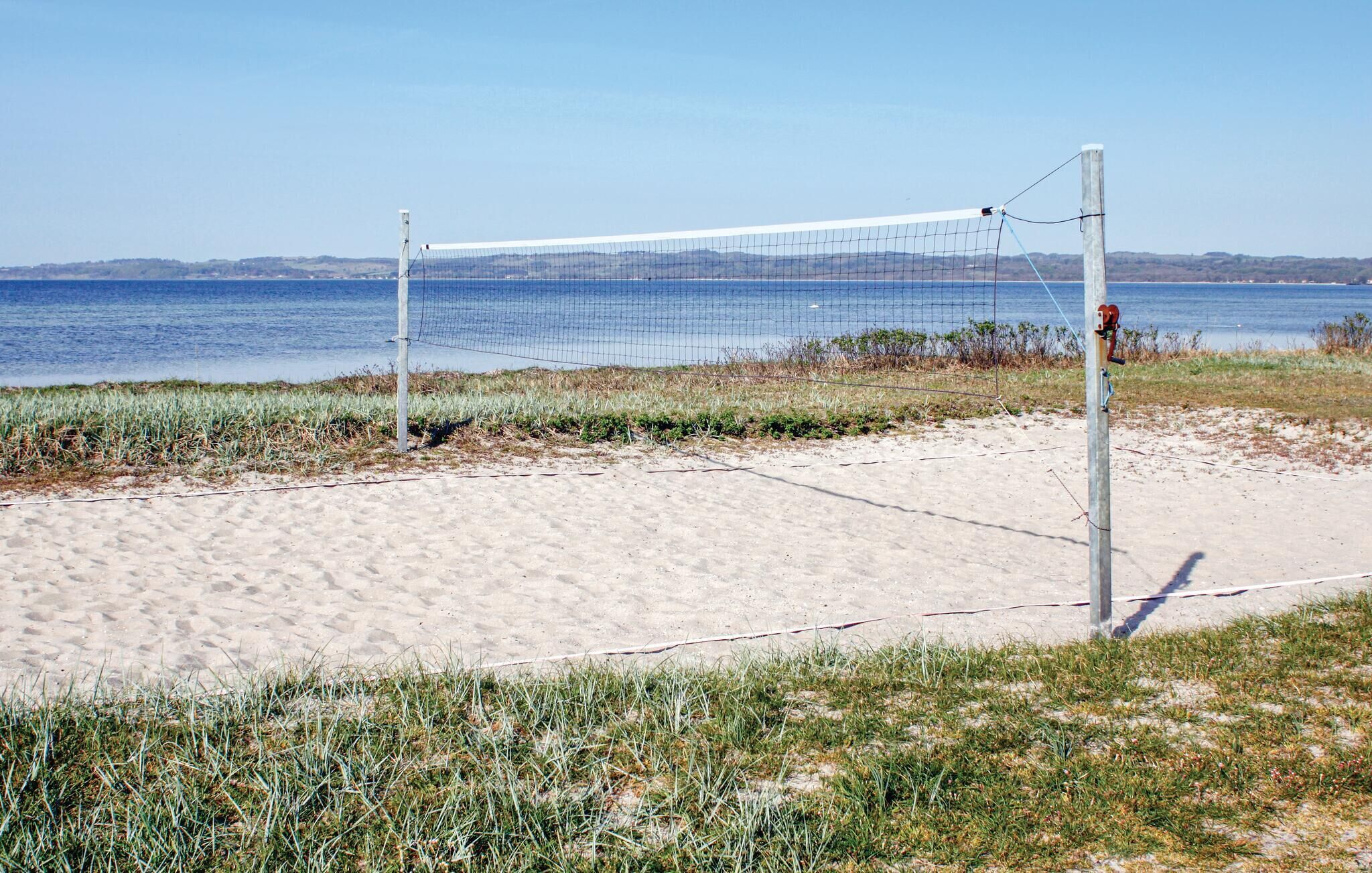 Un filet de volley-ball de plage est installé sur une portion de sable, avec la mer en toile de fond.