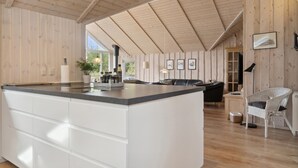 Une cuisine spacieuse avec un grand îlot central, des murs en bois et un plafond haut.