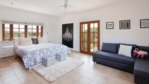 Un dormitorio con cama, sofá gris, alfombra blanca y candelabro.
