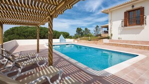 Una piscina con sillas de descanso, una pérgola y vistas del paisaje circundante.