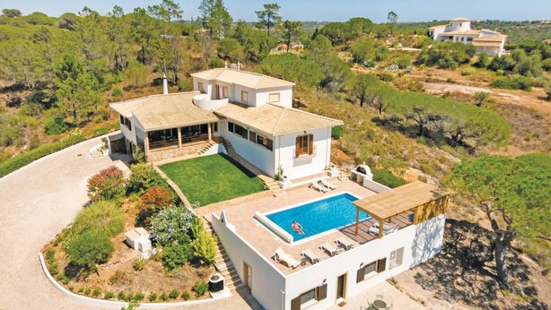 Una villa grande y moderna con piscina, varias habitaciones y una zona de porche cubierta.