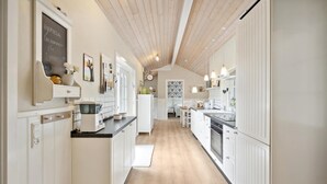 A modern kitchen with white cabinetry, a wooden ceiling, and a central island.