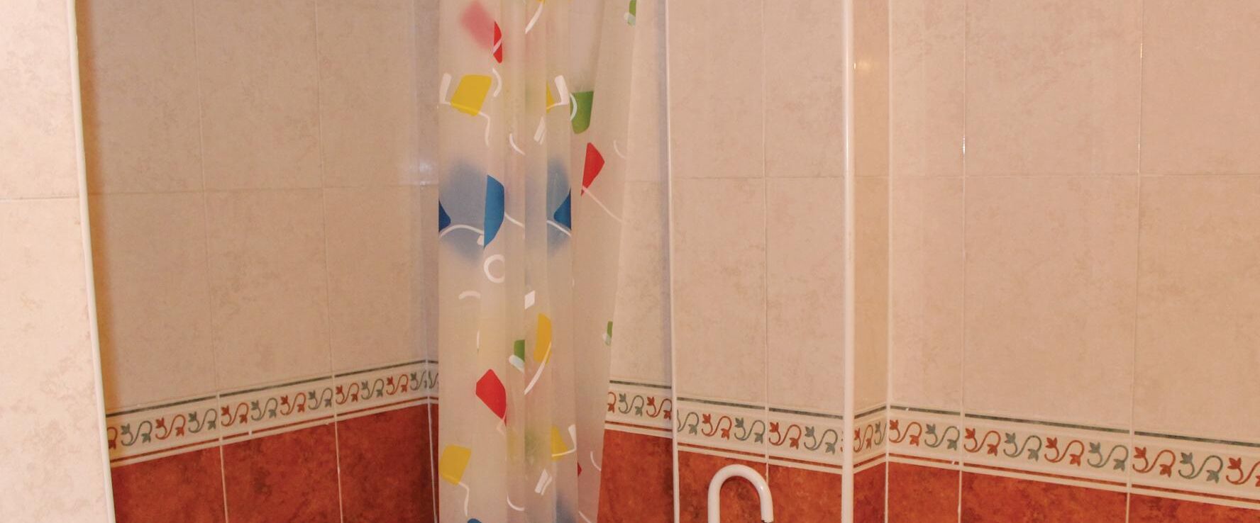 A bathroom with a shower curtain featuring colorful geometric patterns.
