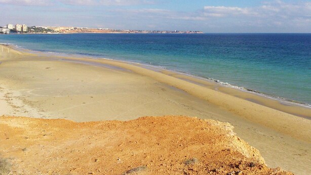 A beach with a sandy shore and a clear view of the ocean.