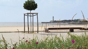 A beach with a wooden structure, a bench, and a lighthouse in the background. - Amazing home in Rioux (Rioux)