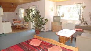 A cozy room with a bed, a small table, a TV, and a dining area with chairs and a table.