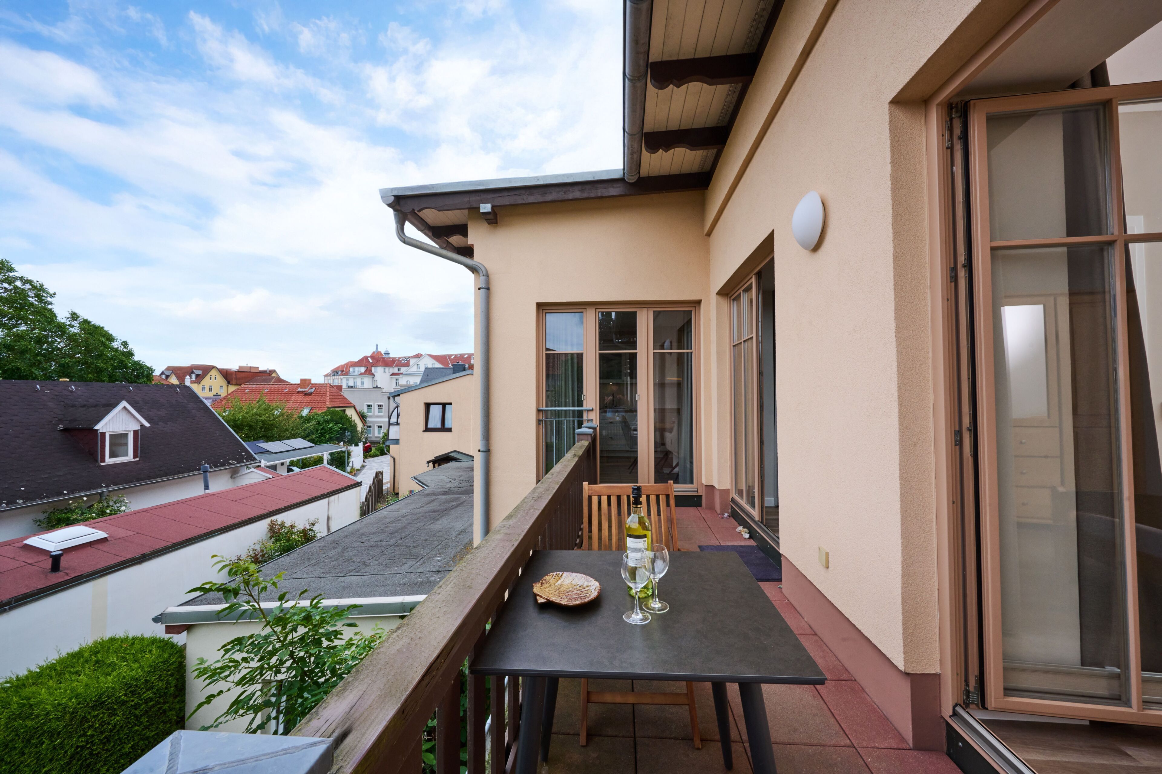 Ein Balkon mit Tisch, Stühlen, einer Weinflasche und einem Glas.