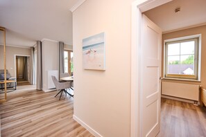 Une pièce spacieuse avec un plancher en bois, un coin repas comprenant une table et des chaises, et une grande fenêtre donnant sur l’extérieur.