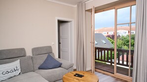 A modern living room with a grey sofa, a round wooden coffee table, and a sliding glass door leading to a balcony. - Residence Seestern Whg S-21 .. - See-21 (Kühlungsborn)