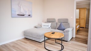 A living room with a sofa, a coffee table, and a painting of sailboats. - Residence Seestern Whg S-21 .. - See-21 (Kühlungsborn)
