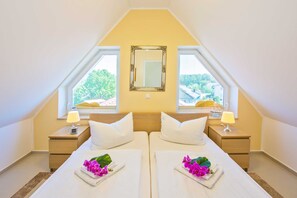 Une chambre double avec deux lits, un grand miroir et deux tables de chevet avec des lampes.