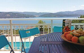 Una terraza con una mesa, sillas y un cuenco de fruta.
