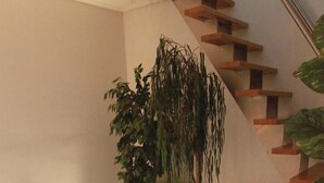 A modern staircase with a glass railing, wooden steps, and potted plants.
