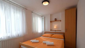 A bedroom with a bed, a radiator, a wooden wardrobe, and a shelf with a lamp. - Holiday apartment mit Terrasse (Čižići)
